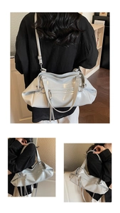 Detail of glossy light grey tote bag with silver zippers and long tassel charms