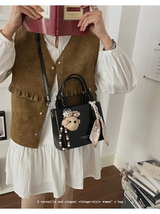 Detail of black vintage mini bag with bear pendant and silk scarf on a handle