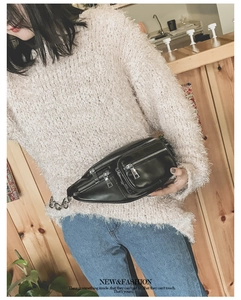 Détail du sac banane noir multi-fermetures avec chaîne argentée sur pull en peluche