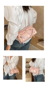 Detail of pink cylindrical baguette bag with silver hardware and moto-style studs