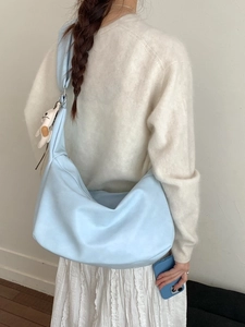 Light blue large capacity hobo bag with teddy bear charm shown on model in minimal style
