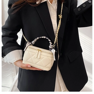 Detail of white quilted mini bag with black and white scarf wrapped on the handle