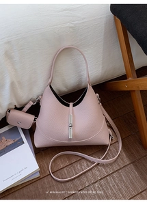 Detailed shot of pink pebble leather shoulder bag with silver hardware on wood floor