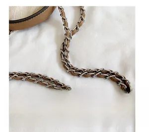 Detailed close-up of the silver metal chain braided with brown leather bag strap
