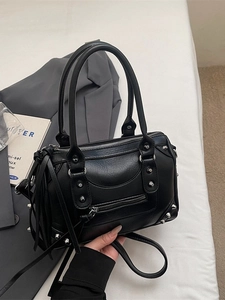 Retro black rivet Boston bag with silver studs and long tassels on textured surface