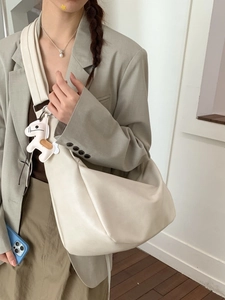 Minimalist beige dumpling tote bag in soft faux leather with a cute horse charm