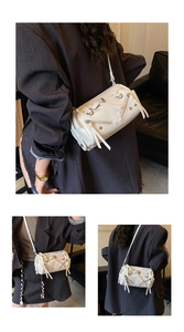 Detail of white cylinder crossbody bag with silver decorative zippers and metal rivets