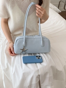 Minimalist light blue bowling bag with star charm shown on white dress with phone