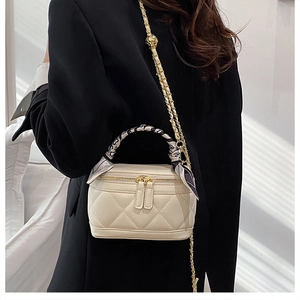 Detail of cream quilted vanity bag with silk scarf handle and chain strap