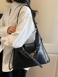 Sac à main chic en cuir noir avec boucles dorées et bandoulière porté par un mannequin