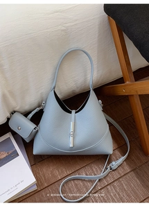 Detail of light blue lychee pattern leather handbag with silver clasp and mini pouch