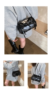Detail of a black punk style crossbody bag featuring silver zippers and glossy finish