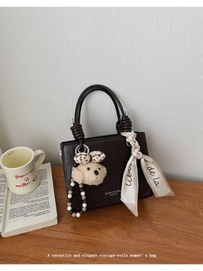 Close-up of a vintage dark brown leather handbag with silk scarf and bear charm