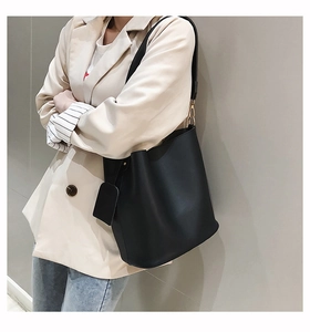 Détail d'un sac seau en cuir noir avec ferrures dorées et pochette latérale chic