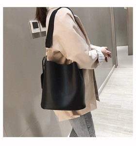 Détail d'un sac seau en cuir noir avec ferrures dorées et bandoulière large