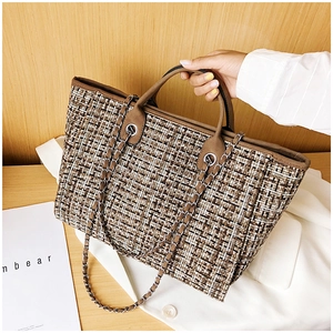 Close-up of checkered tweed tote bag with leather handles and metal chain strap