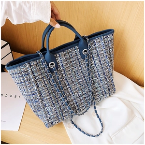 Macro view of blue tweed tote bag showing woven texture, chain strap, and handles