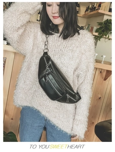 Détail du sac de poitrine en cuir noir avec chaîne métallique et poches zippées