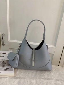 Light blue lychee texture hobo bag with silver lock and mini pouch on white carpet