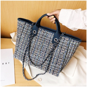 Detailed view of the blue and white tweed texture and chain strap on a tote bag