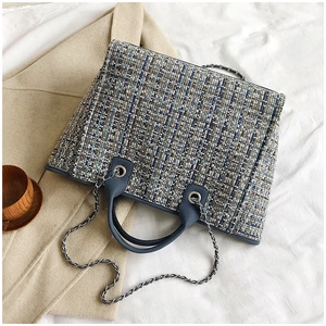Macro shot of plaid tweed tote bag showing texture, chain strap, and blue handle