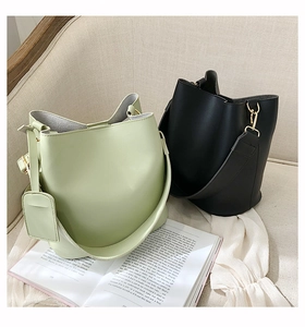 Vue détaillée de sacs seaux élégants en vert et noir sur canapé avec accessoires