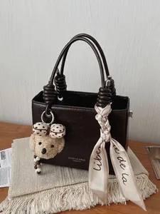 Minimalist brown faux leather handbag with knotted handles and decorative silk scarf