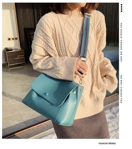 Detail of teal leather crossbody bag with ethnic striped wide strap and gold hardware