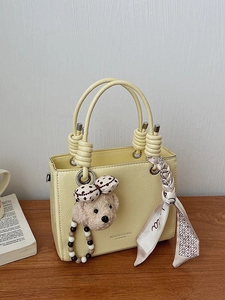 Minimalist cream tote bag with floral scarf and teddy charm on wooden tabletop