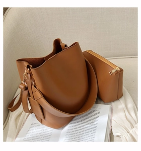 Détail d'un ensemble de sacs seau en cuir marron avec garniture dorée sur canapé beige