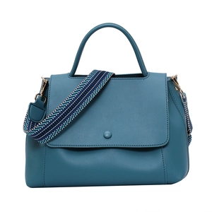 Blue tote bag with round buckle detail and geometric patterned wide shoulder strap