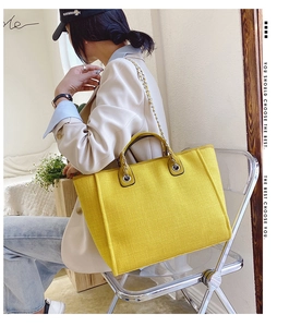 Detail of a bright yellow large-capacity tote bag with chain strap and soft leather finish