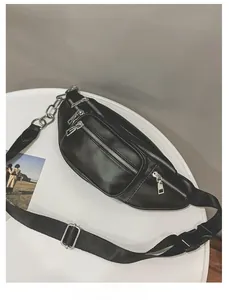 Détail de la sacoche banane en similicuir noir avec fermetures éclair argentées et chaîne