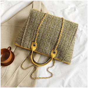 Close-up of yellow and green tweed bucket bag with leather handles and silver chain