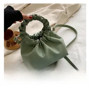 Detail view of light green ruched cloud bag with round handle and soft texture