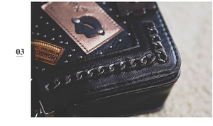 Close-up of textured black leather bag with silver chain, rivets and lip emblem detail