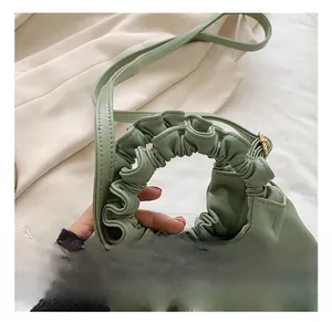 Detail view of the pale green ruched handle and smooth synthetic leather on the bucket bag