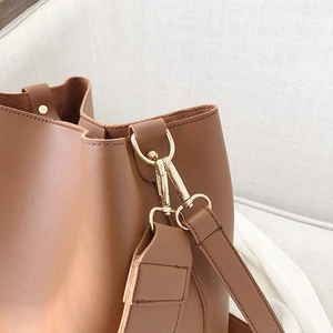 Détail du sac seau en cuir marron avec crochets en métal doré et coutures premium