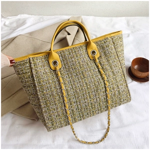 Detailed view of yellow and green tweed bucket bag on beige coat background
