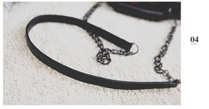 Detail of the black leather strap and metal chain connection on a square crossbody bag