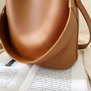 Sac seau minimaliste en cuir caramel sur un magazine ouvert avec une finition nette