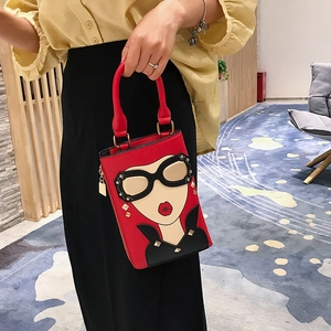 Sac à main rouge style pop art avec motifs cartoon et clous dorés porté sur chemise