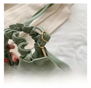 Detail of light green bucket bag showing high-quality gold hardware and pleated handle