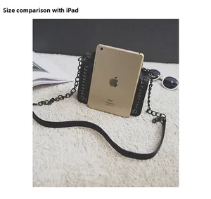 Black PU shoulder bag size comparison with an iPad on a white plush background