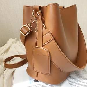 Sac seau marron en cuir grainé avec détails dorés posé sur un magazine de mode élégant