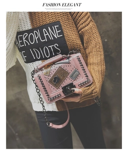 Detail of pink punk style crossbody bag with retro patches, rivets and metal chain trim