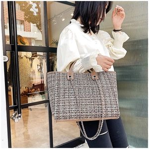 Detail of tweed weave texture and metal chain strap on large tote bag for daily commute