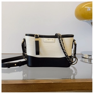 Detail of crocodile pattern on black and white bucket bag with chain and leather strap