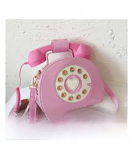 Detailed close-up of pink rotary phone-shaped handbag featuring glossy patent leather finish