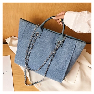 Detail of blue woven tote bag with silver chain strap and durable canvas texture